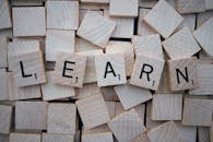 Wooden letter tiles arranged to spell 'learn' on a background of scattered tiles.
